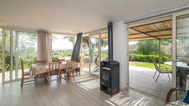 A spacious room with a large sliding glass door, a built-in wood stove, a dining area with a table and chairs, and a view of the outdoors.