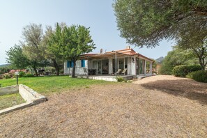 A house with a covered porch, a garden with a gravel path, and trees.