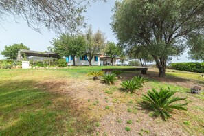Une maison dotée d’un patio, entourée d’arbres et d’une pelouse verdoyante.