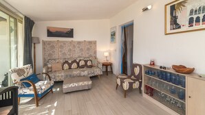A living room with a sofa, armchairs, a small table, and a cabinet with glassware.