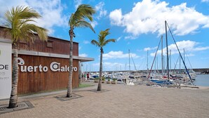 A marina with boats, palm trees, and a building with 'Puerto Calero' signage. - Villa 'Malvasia 22' with Sea View, Heated Pool, Balcony, A/C & Wi-Fi (Puerto Calero)