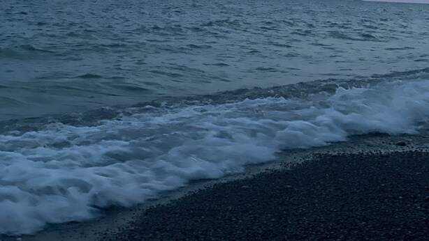 Une plage avec des vagues et un ciel nuageux.
