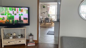 Un salon avec un téléviseur, une console en bois et un canapé gris.