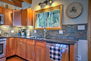 A kitchen with wooden cabinets, a stone backsplash, a large window, and a stainless steel refrigerator. - Big Mountain View’s -  Hiking - Quite Nature Emerson (Swannanoa)