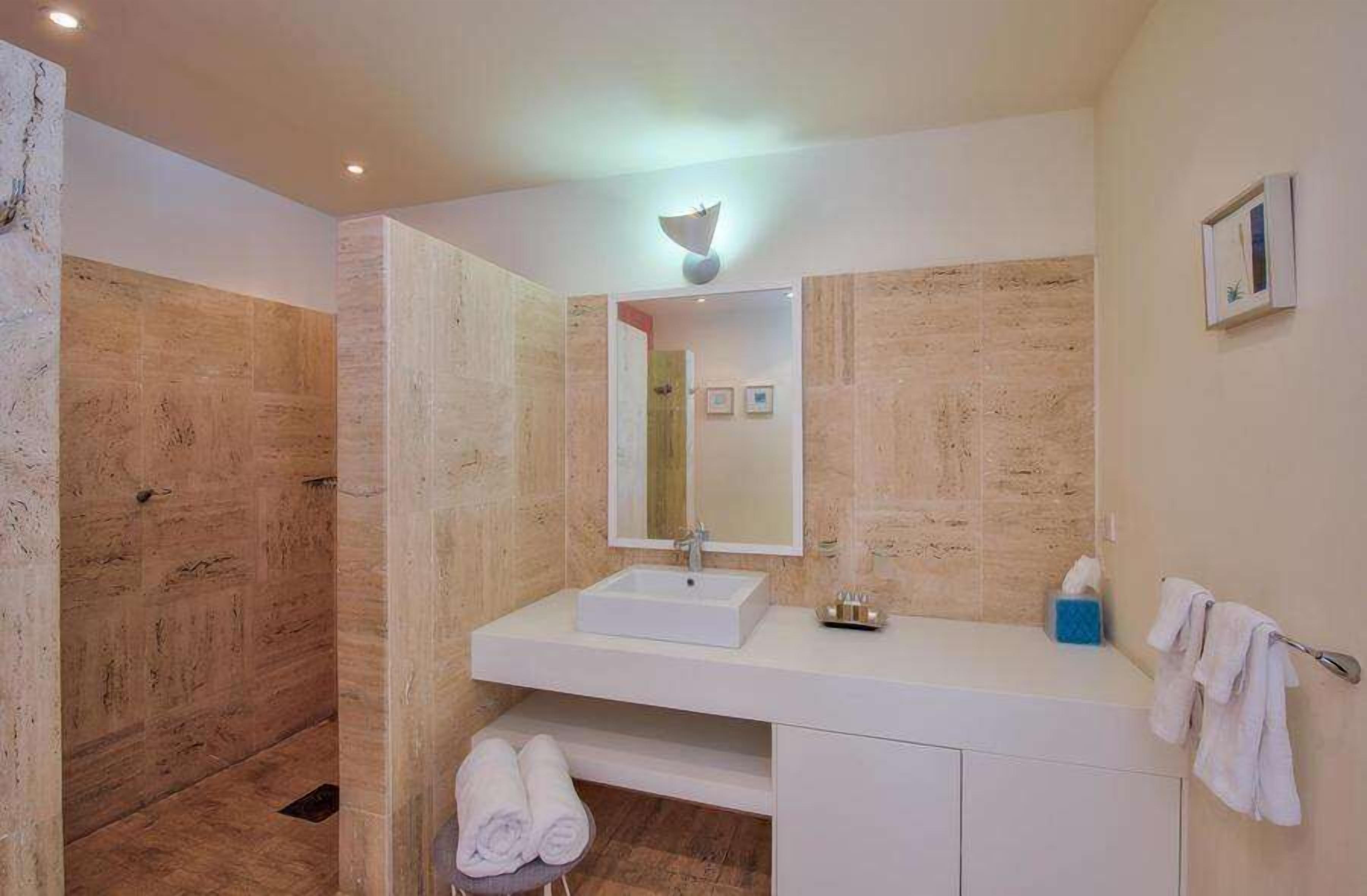 Een moderne badkamer met een witte wastafel, spiegel en douche.