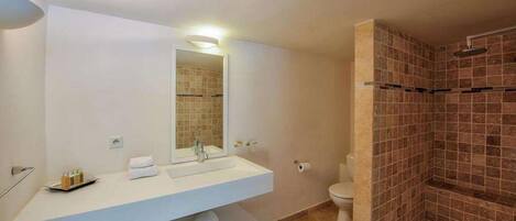 Un baño moderno con un tocador blanco, un espejo grande, un inodoro y una zona de ducha con paredes de azulejos.
