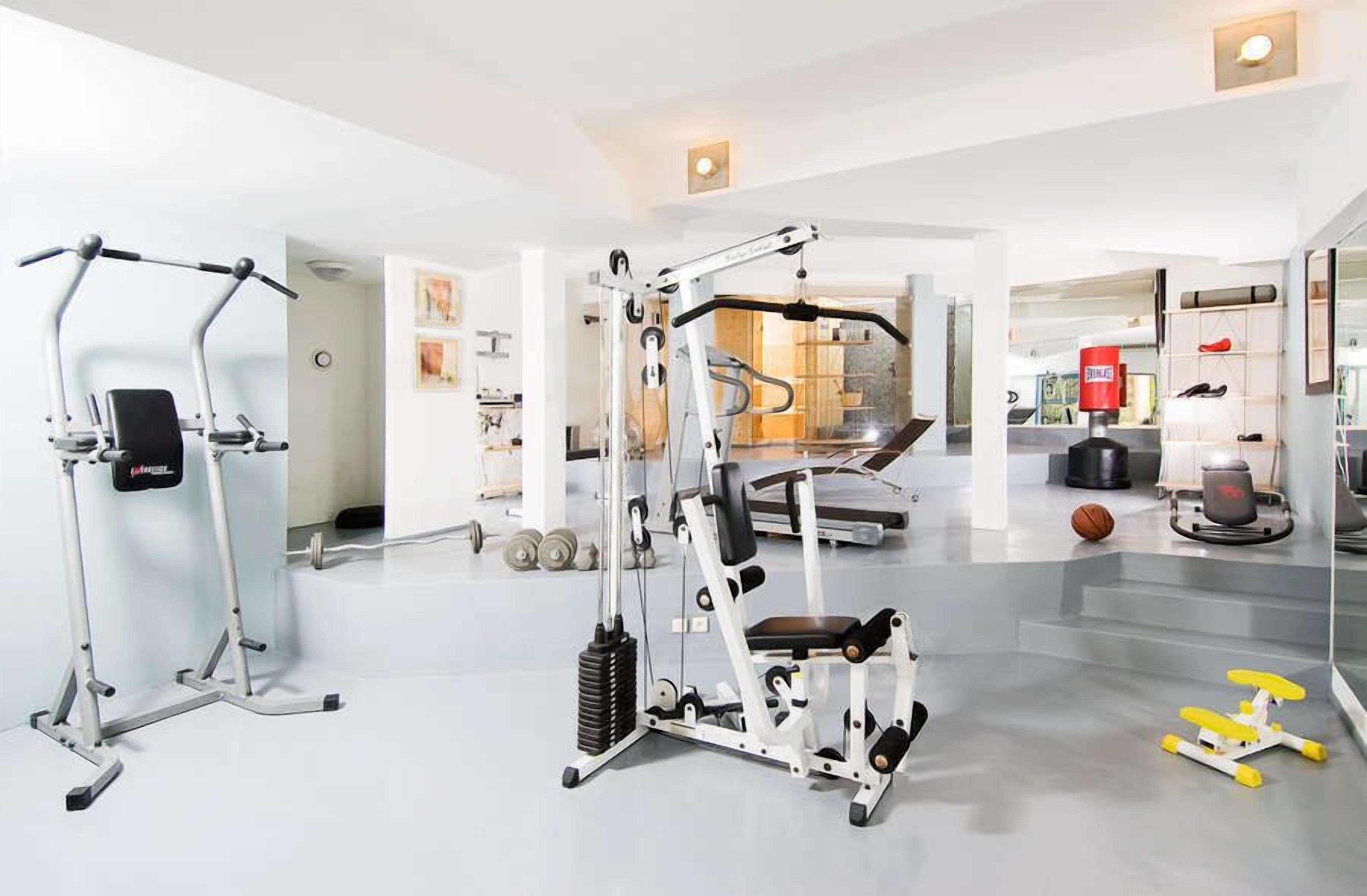 A modern gym with various exercise equipment, a mirrored wall, and a shoe display.