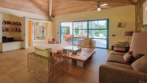 A spacious living area with a high ceiling, a large window, and a view of the outdoors. - Les Palmiers Bleus Luxury villa (Les Terres Basses)