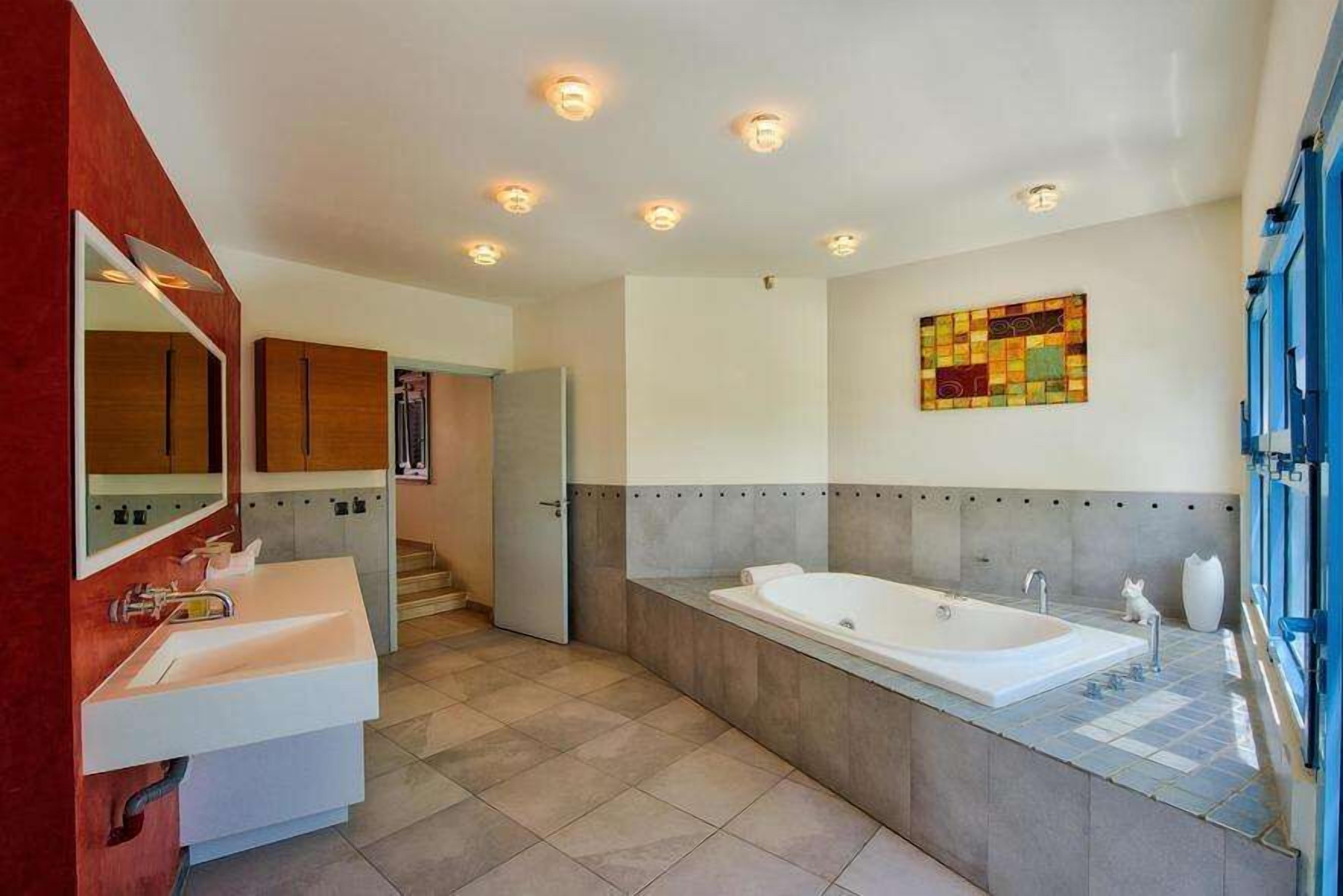 Une salle de bain moderne avec une grande baignoire, un meuble-lavabo à deux vasques et un miroir.