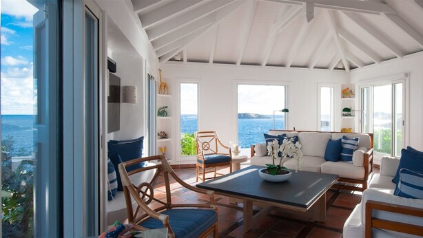 A sunlit room with a view of the sea, featuring a table, chairs, and a sofa. - Cap Au Vent (2/4 Rooms) (Pointe Milou)