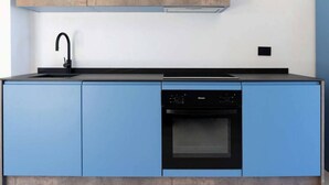 Een moderne keuken met blauwe kastjes, een zwarte kraan en een inbouw vaatwasser.
