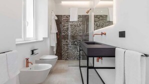 Een moderne badkamer met een witte wastafel, een bad en een douche.