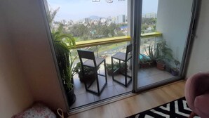 Een balkon met twee stoelen, een tafel en hangende lampen.
