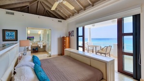 A bedroom with a large bed, a bathroom, and a balcony with a view of the ocean. - Beautiful Bahari Luxury villa (Simpson Bayv)
