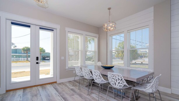 A dining area with a table, chairs, and a chandelier. - New!! Steps To Beach, Gulf Views, Private Heated Pool (Panama City Beach)