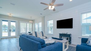 A spacious living room with a blue sofa set, a coffee table, and a flat-screen TV mounted on the wall. - New!! Steps To Beach, Gulf Views, Private Heated Pool (Panama City Beach)