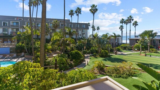 Un albergo con piscina, palme e campo da golf.