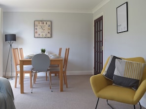 Un comedor con una mesa de madera, sillas y un reloj en la pared.