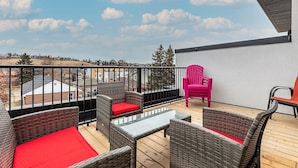A balcony with wicker furniture, a glass table, and a red chair. - Executive home, Rooftop Deck, close to Foothills Med Ctr, Kensington Plaza & DT (Calgary)