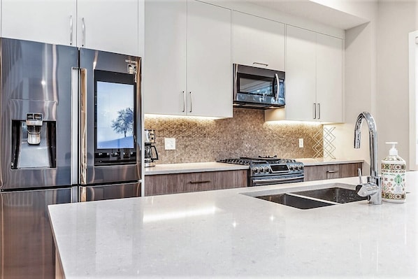 A modern kitchen with stainless steel appliances, a built-in oven, and a coffee machine.