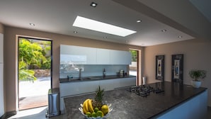 Een moderne keuken met een groot eiland, een inbouwoven en uitzicht op de omgeving.
