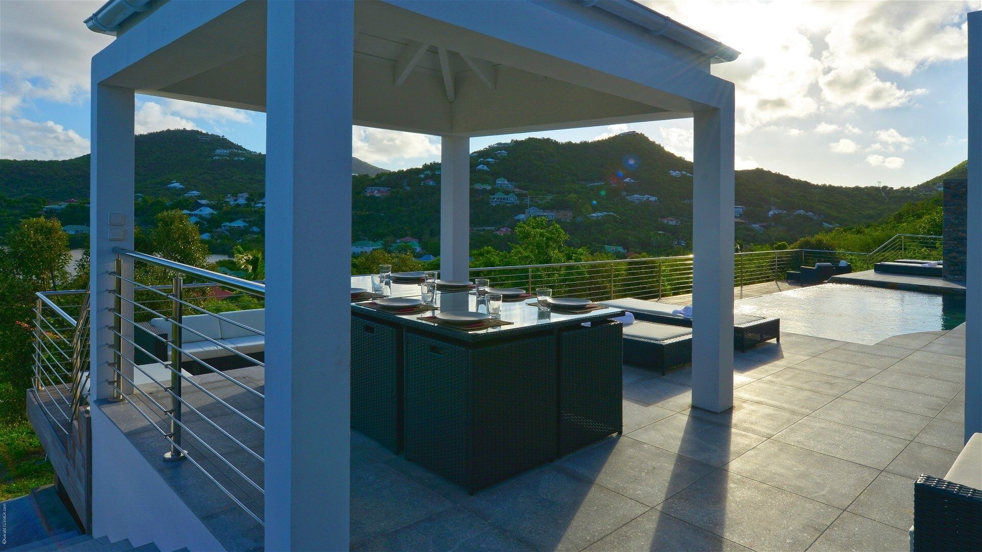Un espace extérieur abrité comprenant une piscine, un coin repas et offrant une vue sur un paysage montagneux.