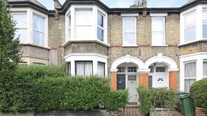 A row of terraced houses with bay windows and a front door with a small porch.