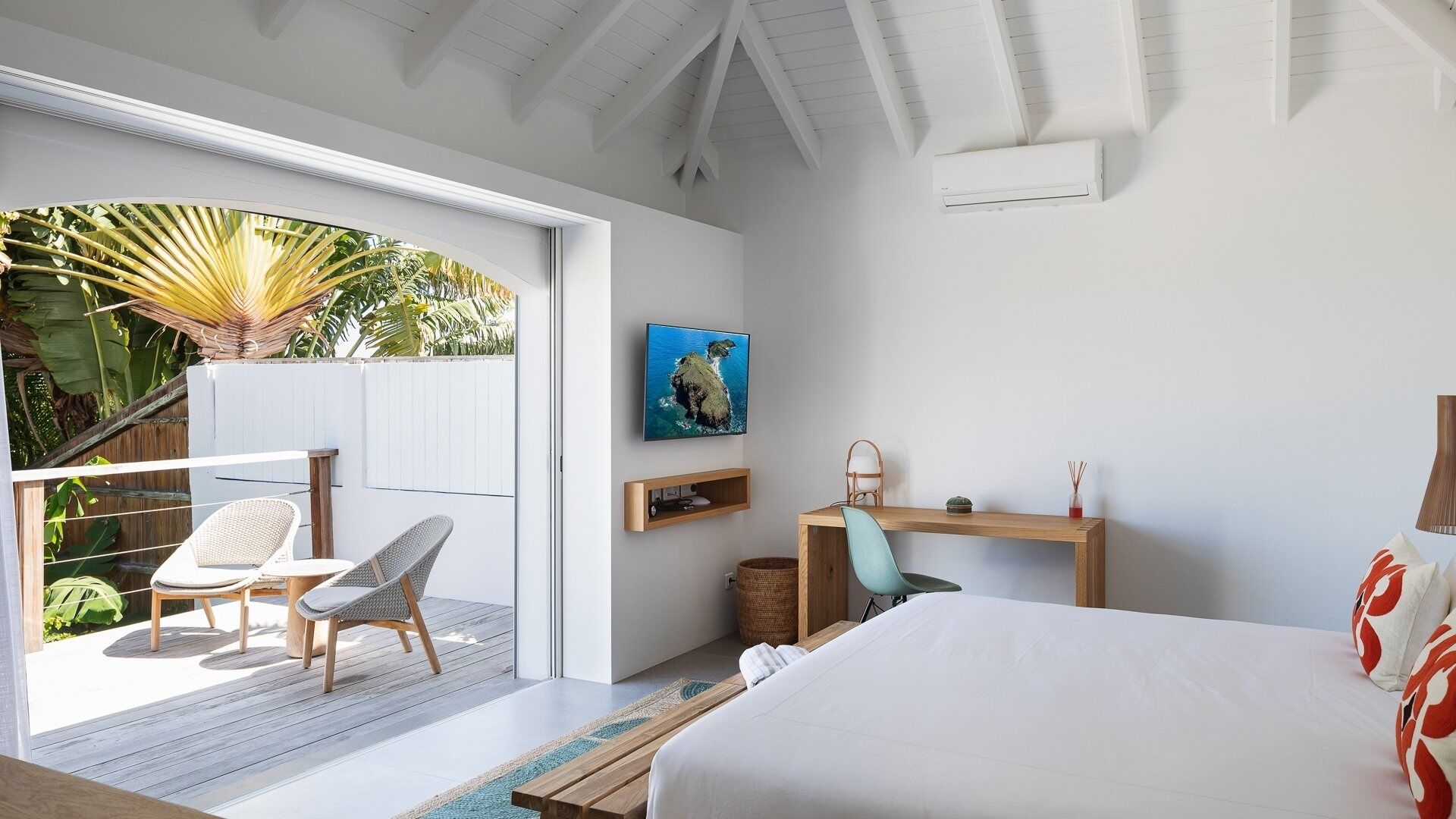 Una camera da letto con un letto, una scrivania, una sedia, una televisione e vista sull'esterno.