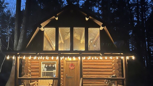 A log cabin with a porch, outdoor seating, and a fireplace. - Rustic MT Cabin (Kalispell)