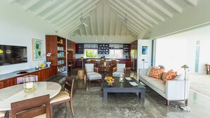 Un espacio habitable amplio con techo alto, una mesa de comedor, un sofá y una cocina al fondo.
