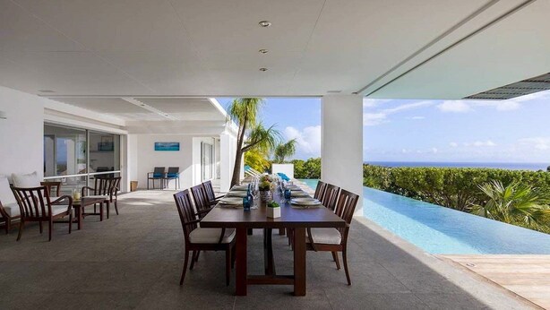Un comedor con vistas al océano, una piscina y un paisaje tropical.