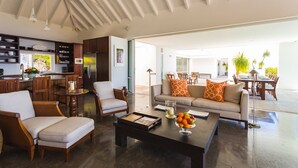 A spacious living area with a sofa, chairs, a coffee table, and a kitchen in the background. - Bellissima (2/3 Rooms) (Gouverneur)
