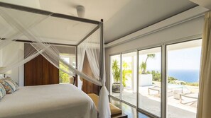Une chambre à coucher avec un lit à baldaquin, de grandes fenêtres et une vue sur l’extérieur.