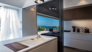 Eine moderne Küche mit einem großen Fenster, einer integrierten Spüle und Blick auf den Ozean.