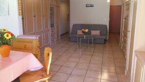 Un espace de vie compact comprenant un coin repas, un canapé et une kitchenette.