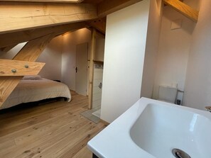 Une chambre avec un plafond en pente en bois, une baignoire blanche et un lit en bois.
