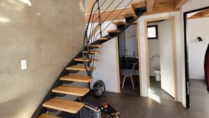 Ein modernes Interieur mit einer Holztreppe, einer Betonwand und einem Fliesenboden.