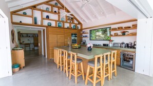 Une cuisine moderne dotée d’un îlot central, de tabourets de bar en bois et d’un ventilateur de plafond.
