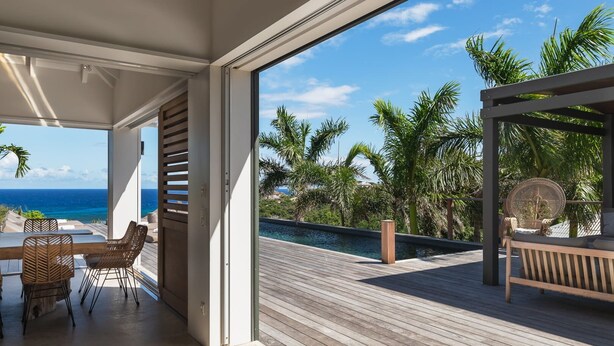 Une terrasse extérieure moderne avec une piscine, des meubles en bois et une vue sur l’océan.