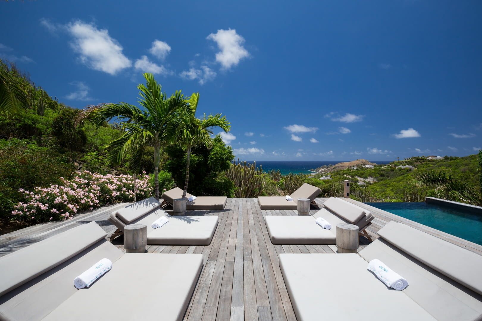 Eine Holzterrasse mit vier Liegestühlen und einem Pool.