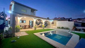 A residential property with a swimming pool, a covered patio, and a car parked in the garage. - Beach house with Wi-Fi, pool, and barbecue. (Lucena)
