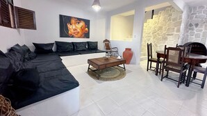 A living room with a sectional sofa, a coffee table, a dining table with chairs, a stone wall, and a painting on the wall. - Beach house with Wi-Fi, pool, and barbecue. (Lucena)