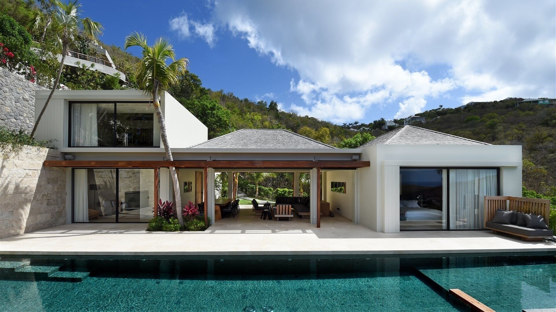 A modern two-story house with a pool, large windows, and a patio area.