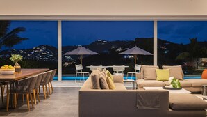 Ein moderner Außenbereich mit Pool, Sitzgelegenheiten und Blick auf eine nächtliche Skyline.