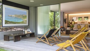 A modern living room with a large window overlooking a scenic coastal view, wooden furniture, and a cozy seating area.