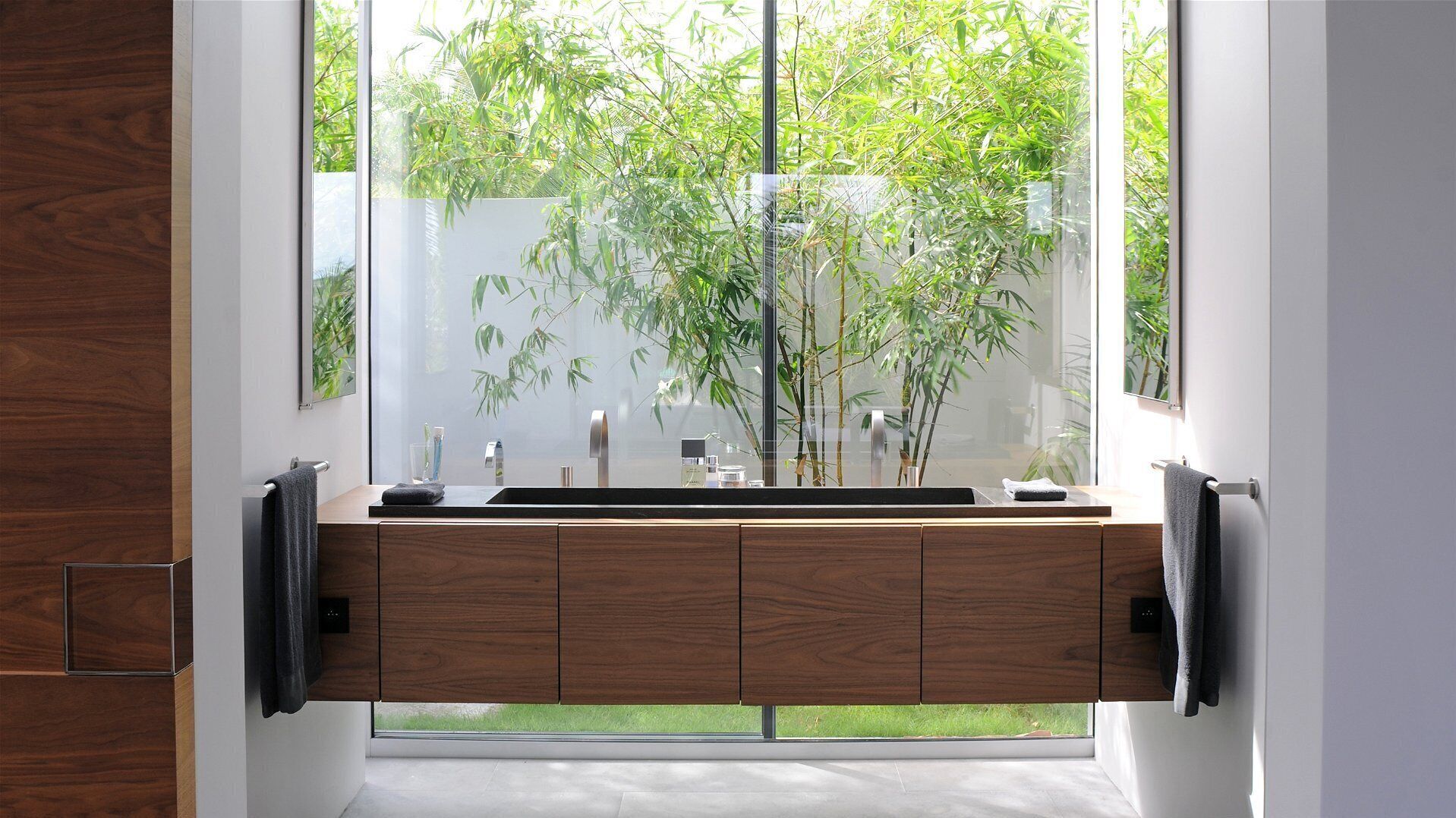 Un baño moderno con tocador de madera, un ventanal grande y vistas al exterior.