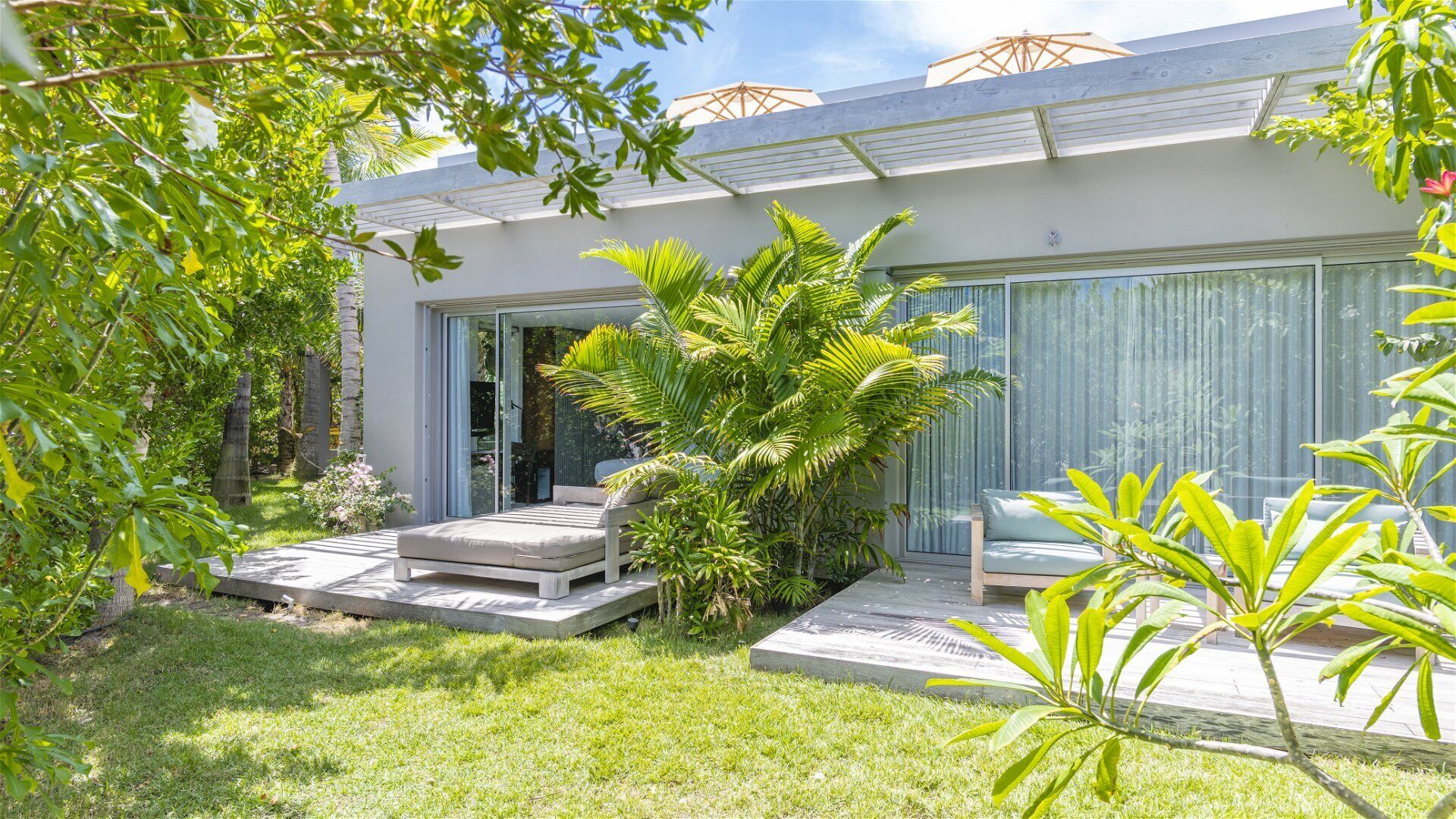 A modern house with a patio area, a sliding glass door, and a small outdoor seating area with a bench and a table.