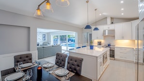 Een moderne keuken met witte kasten, een centraal eiland en hanglampen.