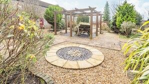 A garden with a wooden pergola, a stone circular seating area, and various plants. - The Parlour - UK37517 (Routh, Beverley)