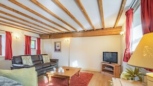 A cozy living room with a wooden ceiling, a leather sofa, a coffee table, and a television. - The Parlour - UK37517 (Routh, Beverley)